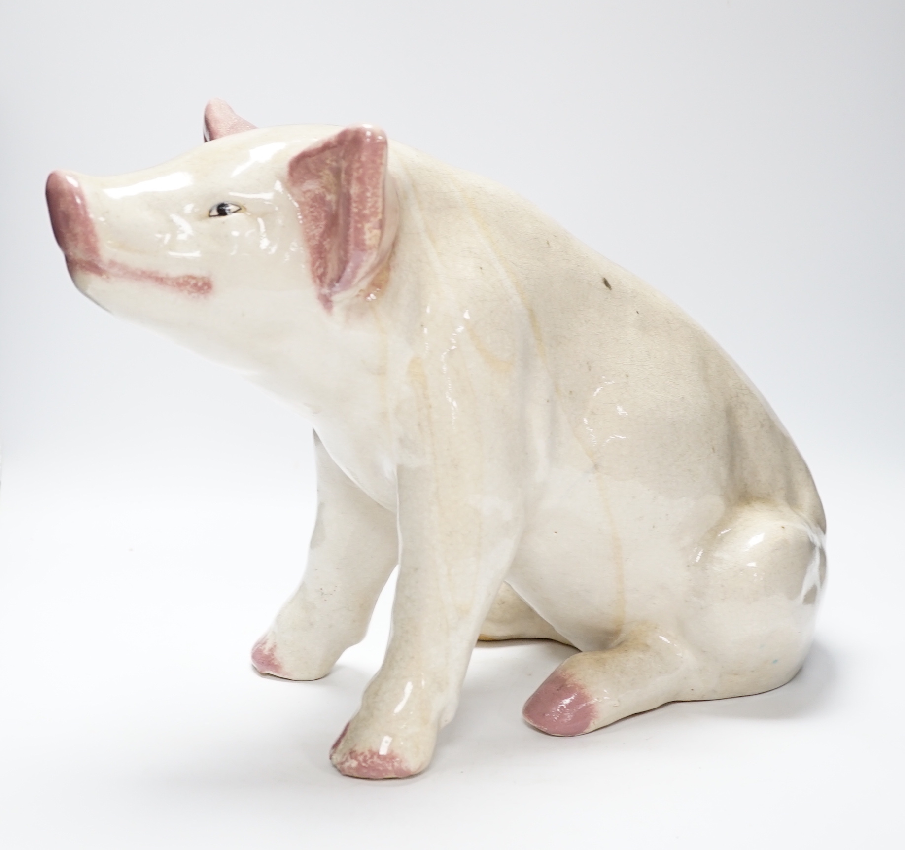 A large earthenware model of a seated piglet, 31cm high